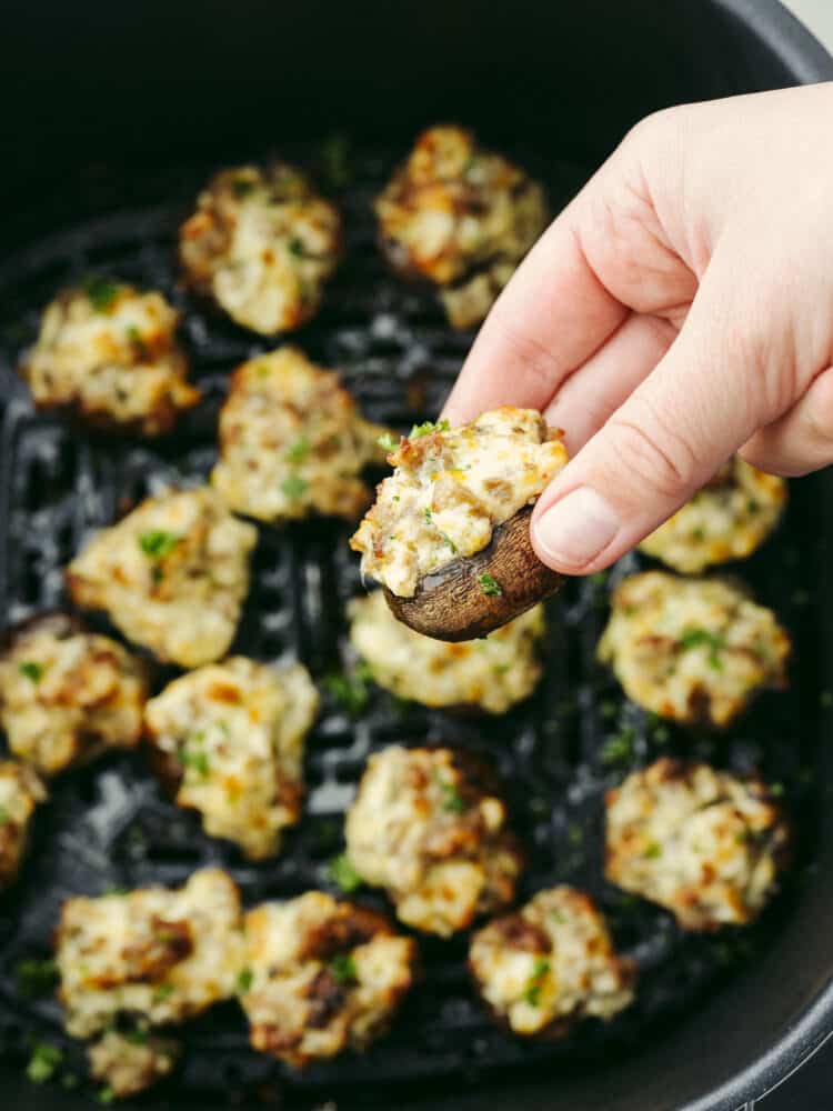 The perfect bite-sized appetizer, air fryer sausage stuffed mushrooms are hearty and meaty with a flavorful sausage filling your family won't be able to get enough of! They work great as both an appetizer and a side dish to complement your favorite meals! Picking up a cooked stuffed pepper out of an air fryer basket.