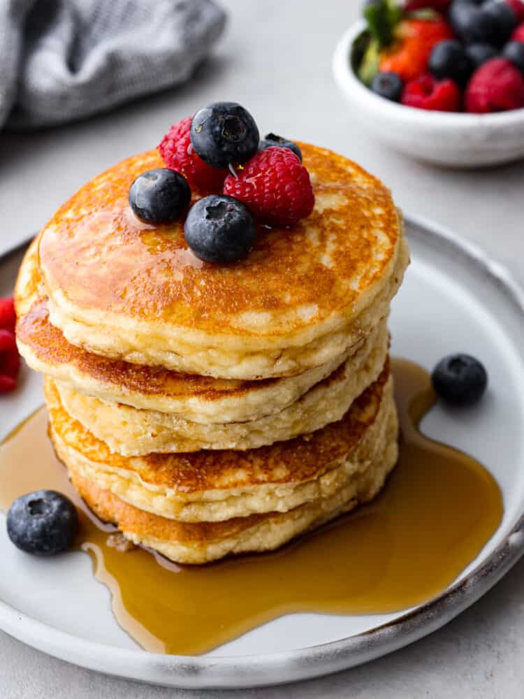 Sweet, fluffy, and keto-friendly! These delicious keto pancakes are a simple and healthy brunch option for when your craving a carb-filled breakfast but don't want to mess up your macros. A stack of keto pancakes topped with syrup and berries.