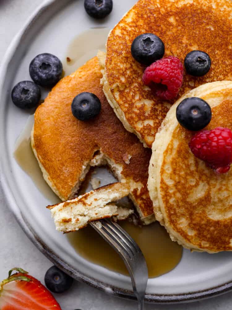 Sweet, fluffy, and keto-friendly! These delicious keto pancakes are a simple and healthy brunch option for when your craving a carb-filled breakfast but don't want to mess up your macros. Closeup of keto pancakes with a bite taken out of them.