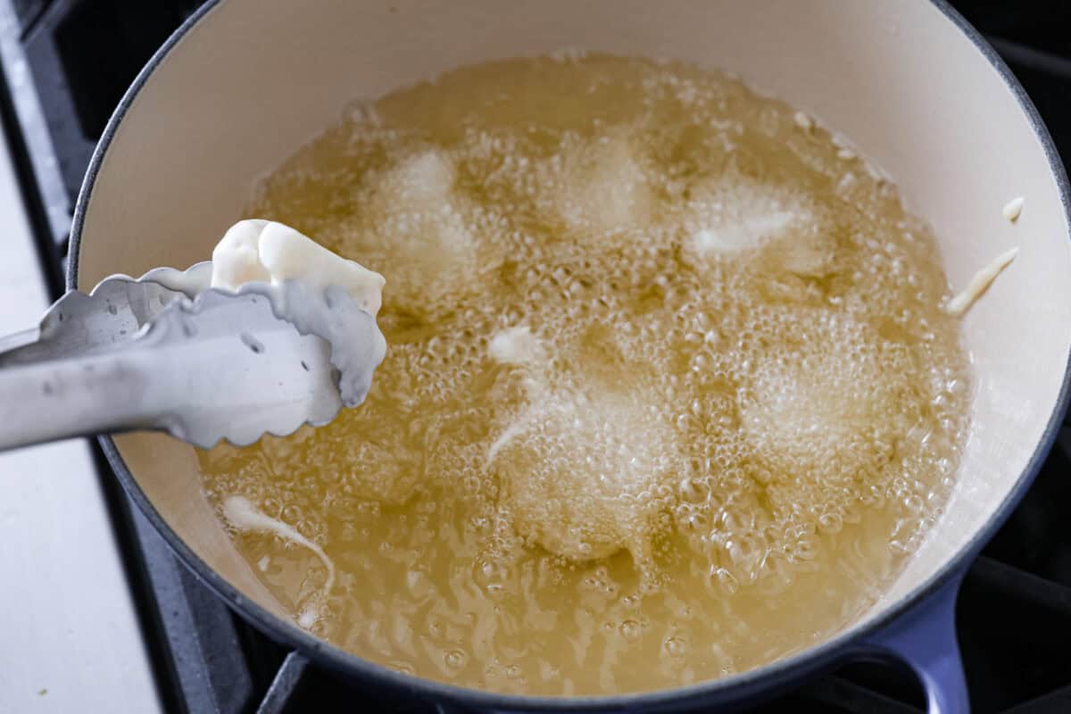 Fried cauliflower is my go-to crispy, low-carb snack that sneaks in some extra veggies and fiber. I make them for my kids all the time. They think they’re just getting a treat, but I know better! Frying dipped cauliflower in oil.
