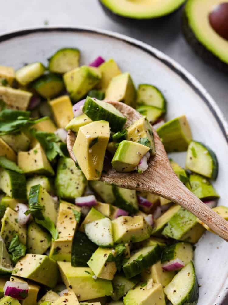 Cucumber avocado salad is the ultimate combination of creamy and crisp, tossed in a mouthwatering dressing made of lime juice, olive oil, and garlic! It's light, flavorful, and perfect for serving alongside all of your favorite summer meals. Closeup of a spoonful of cucumber avocado salad.