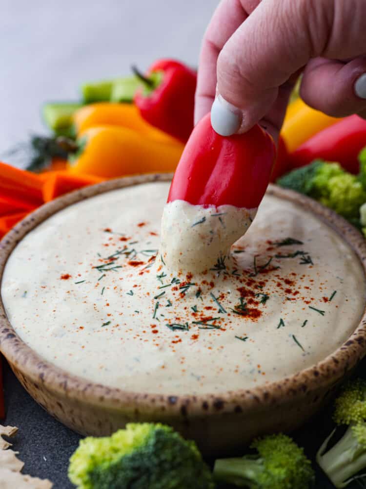 Don't underestimate cottage cheese, because once you taste this flavorful dip loaded with herbs, spices, and hard-boiled eggs (reminiscent of deviled eggs), you'll keep coming back for seconds and thirds. A pepper being dipped into the cottage cheese mixture.